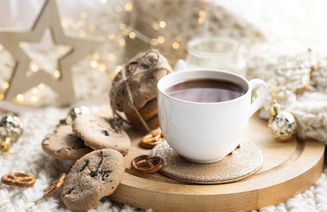 Winterdekoration mit einer Tasse Kakao und Keksen auf einem Holzbrett