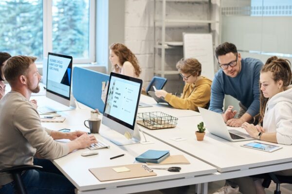 Einige Mitarbeiter sitzen vor Rechnern in einem Büro