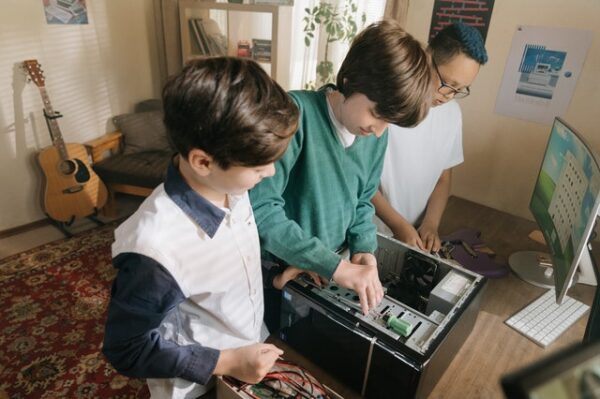 Drei Kinder schrauben an einem Computer