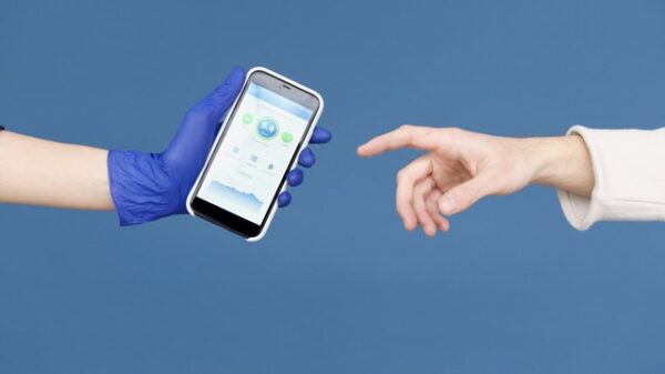 Eine behandschuhte Hand hält ein Smartphone, während eine andere danach greift