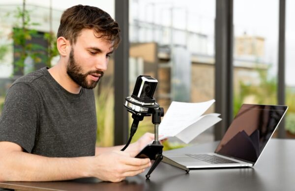 Ein Mann sitzt vor einem Mikrofon und einem Laptop