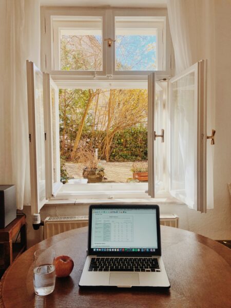 Ein Laptop steht auf einem Tisch vor einem offenen Fenster
