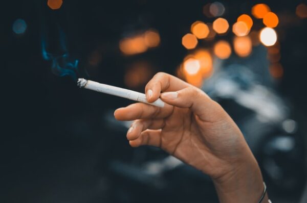 Eine Hand hält eine rauchende Zigarette