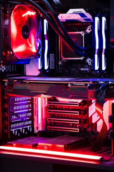 Ein geöffneter Computer. Im Inneren befinden sich verschiedene PC-Componenten mit roten RGB-Lichtern auf einer Hauptplatine