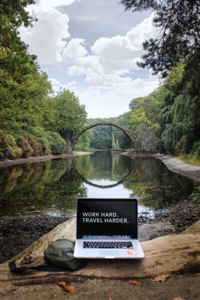 Ein Laptop steht auf einem Felsen vor einer Steinbrücke