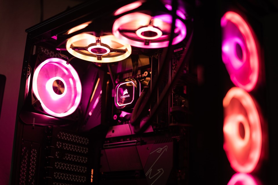 Ein PC mit pink-gelb leuchtenden Lüftern in einem dunklen Raum.