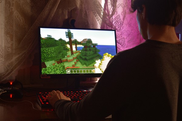 Mann sitzt vor einem Monitor und spielt Minecraft.