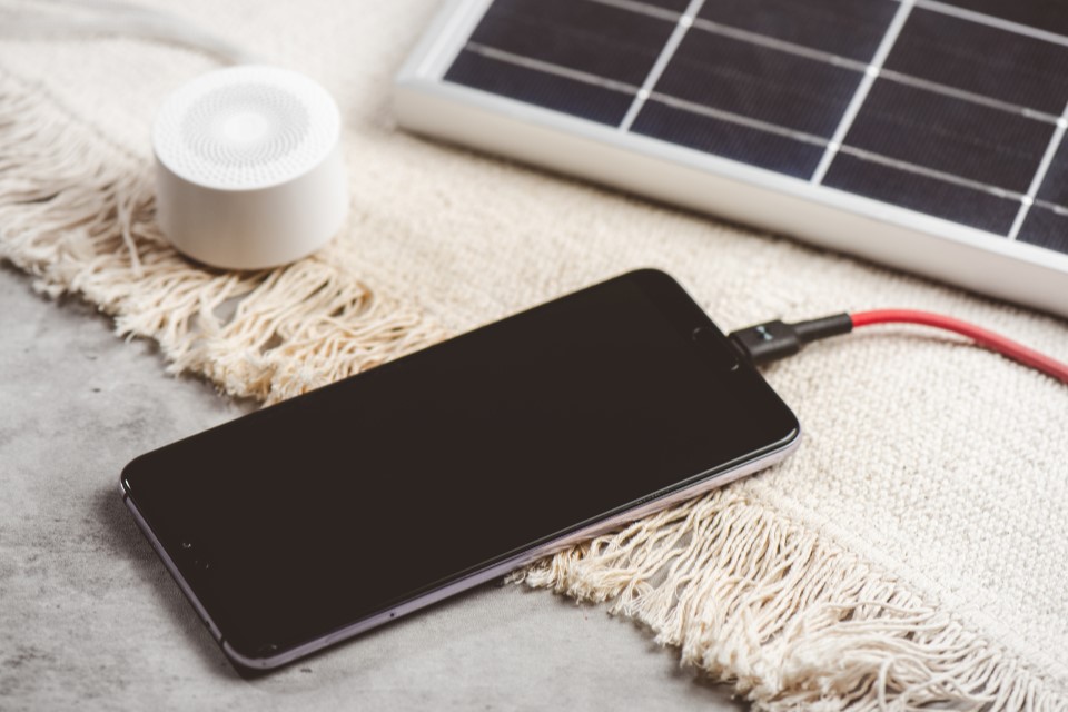 Ein Solarpanel lädt über ein Kabel ein Smartphone.