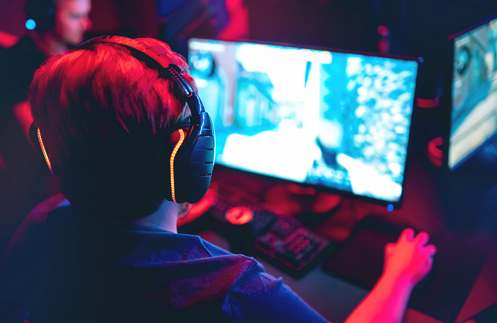 Online-Gamer sitzt mit Headset am Computer und zockt.