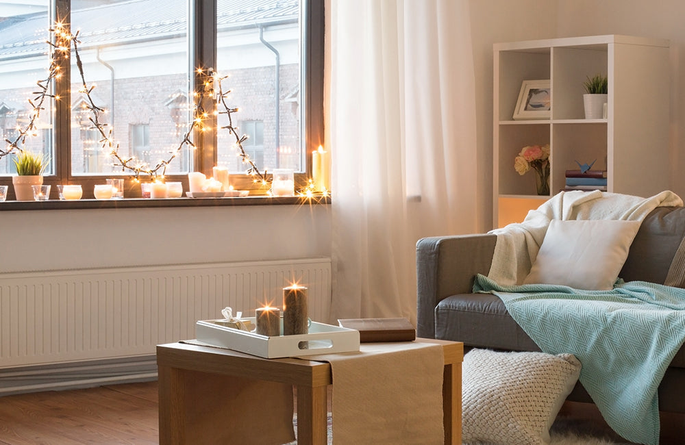 Wohnzimmer, das mit Lichterketten am Fenster und Kerzen geschmückt ist
