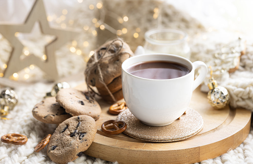 Winterdekoration mit einer Tasse Kakao und Keksen auf einem Holzbrett